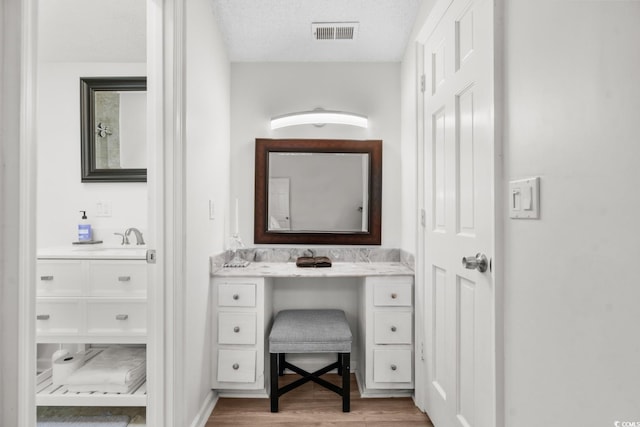 bathroom featuring hardwood / wood-style flooring, vanity, and a textured ceiling