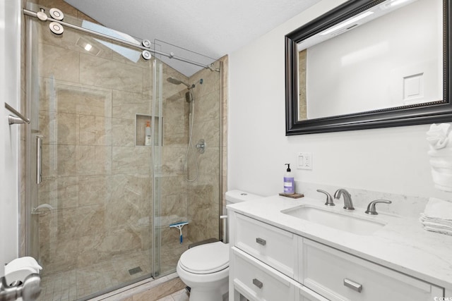 bathroom with vanity, toilet, a shower with shower door, and a textured ceiling