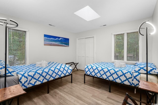 bedroom with a skylight, light hardwood / wood-style floors, and a closet