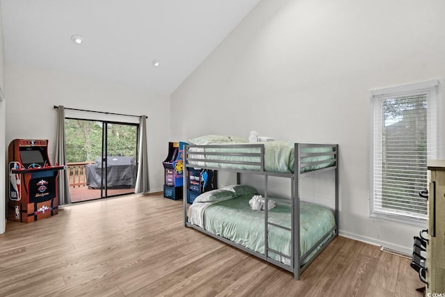 bedroom featuring access to outside, hardwood / wood-style floors, and high vaulted ceiling