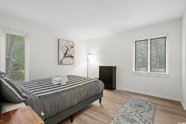 bedroom featuring light wood-type flooring and a textured ceiling