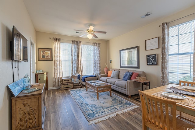 living room with baseboards, wood finished floors, visible vents, and ceiling fan