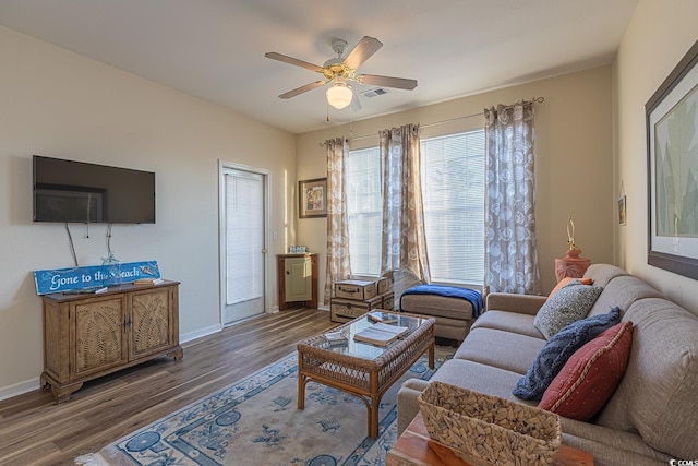 living room with baseboards, wood finished floors, visible vents, and ceiling fan