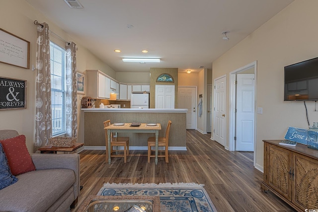 kitchen featuring white cabinets, a peninsula, dark wood-style floors, freestanding refrigerator, and visible vents