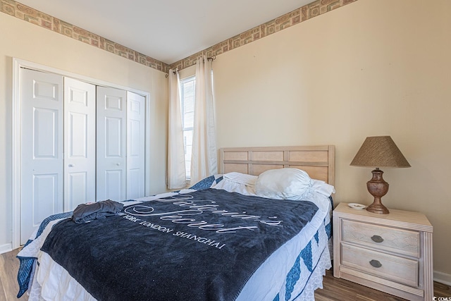 bedroom with baseboards, wood finished floors, and a closet