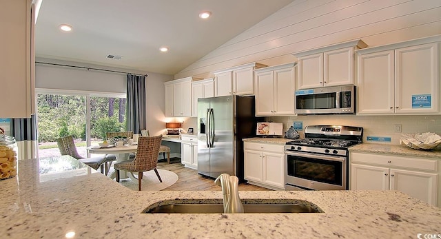 2038 Lone Cypress Dr, Myrtle Beach, SC 29579 - kitchen with appliances with stainless steel finishes, light stone counters, lofted ceiling, and sink