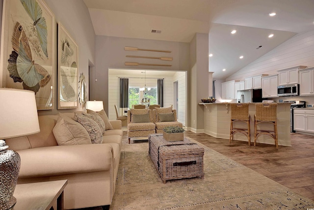 2038 Lone Cypress Dr, Myrtle Beach, SC 29579 - living room with wood walls, an inviting chandelier, high vaulted ceiling, and light wood-type flooring
