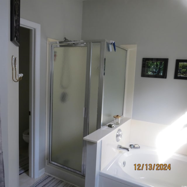 bathroom featuring tile patterned floors, toilet, and shower with separate bathtub