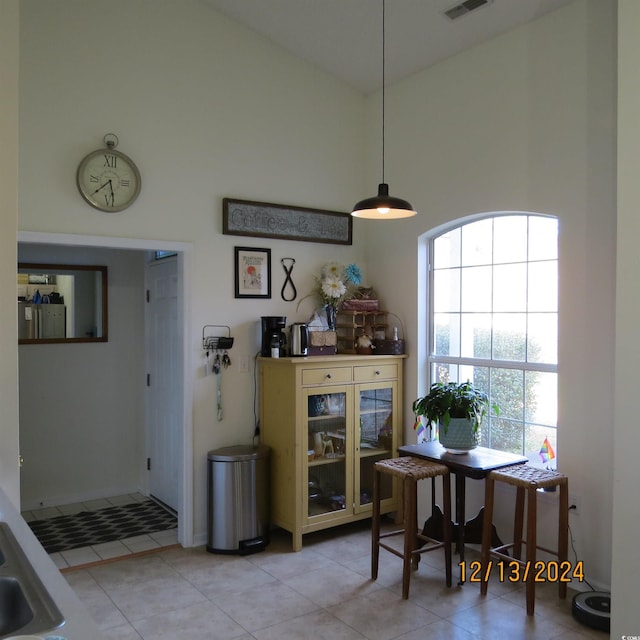 dining area featuring light tile patterned floors and a towering ceiling