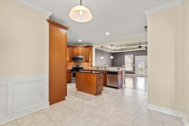 kitchen featuring a center island, ceiling fan, ornamental molding, kitchen peninsula, and stainless steel appliances