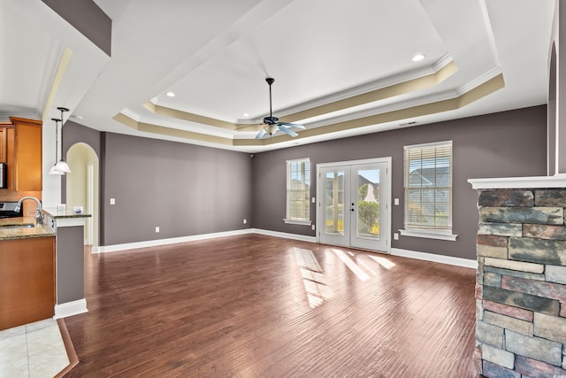 living room featuring dark wood-type flooring, french doors, sink, ceiling fan, and a tray ceiling