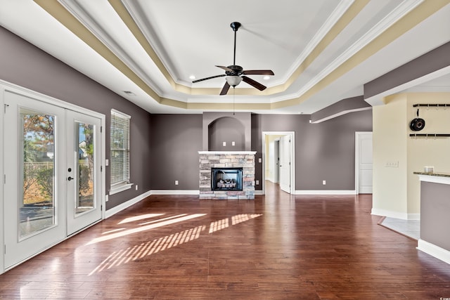 unfurnished living room featuring a raised ceiling, crown molding, dark hardwood / wood-style flooring, and ceiling fan