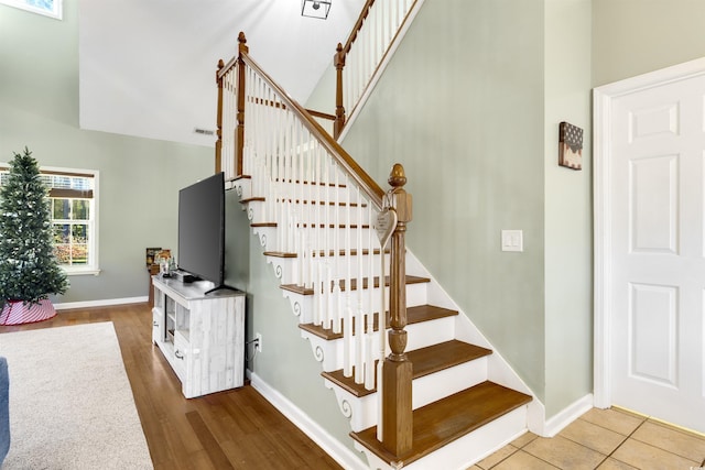 stairway featuring high vaulted ceiling and hardwood / wood-style flooring