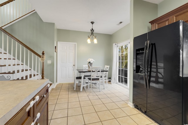 kitchen featuring black fridge, light tile patterned floors, hanging light fixtures, and a notable chandelier