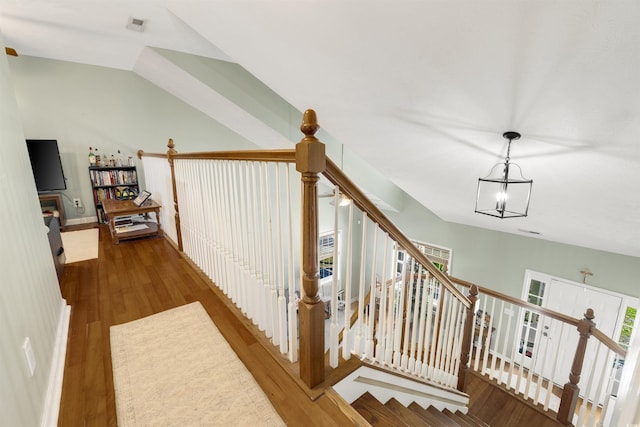 stairway with hardwood / wood-style flooring, an inviting chandelier, and lofted ceiling