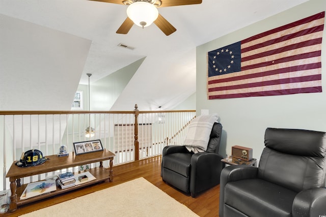 living area featuring ceiling fan, hardwood / wood-style floors, and vaulted ceiling