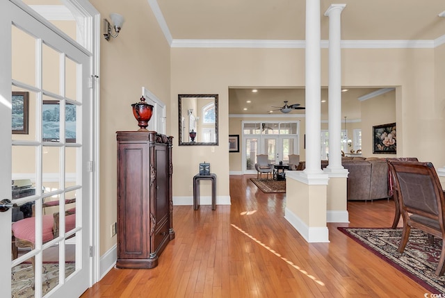 entrance foyer featuring ceiling fan, light hardwood / wood-style floors, ornamental molding, and decorative columns