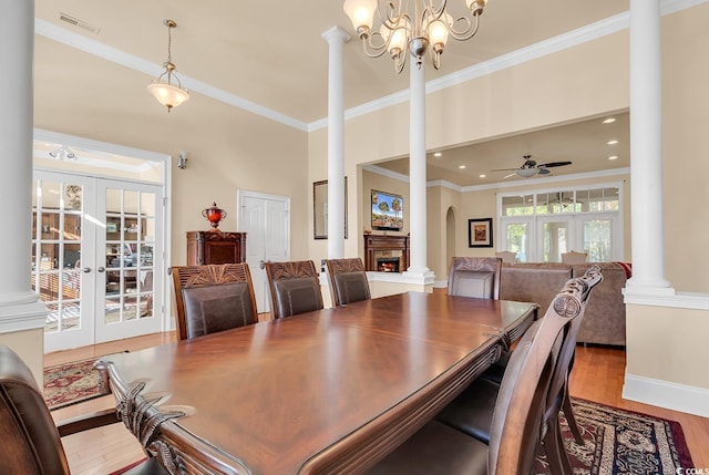 dining area featuring hardwood / wood-style flooring, ceiling fan with notable chandelier, ornamental molding, and french doors