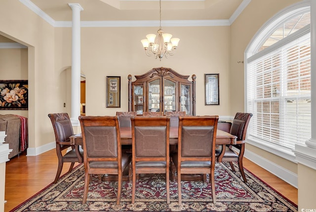 dining room featuring a chandelier, light wood-type flooring, ornate columns, and crown molding