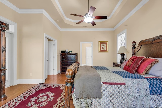 bedroom with a raised ceiling, ceiling fan, ornamental molding, and hardwood / wood-style flooring