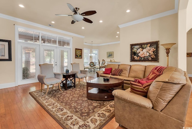 living room with ceiling fan with notable chandelier, french doors, light wood-type flooring, and crown molding