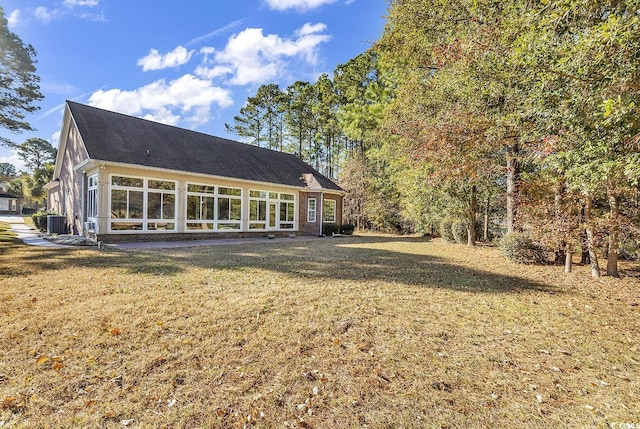 back of property featuring central AC unit, a sunroom, and a yard