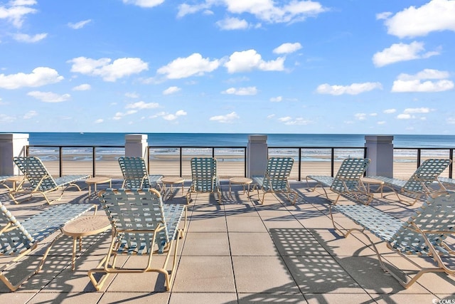 view of patio featuring a water view and a beach view