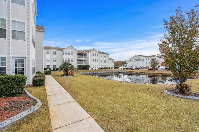 view of property's community featuring a lawn and a water view