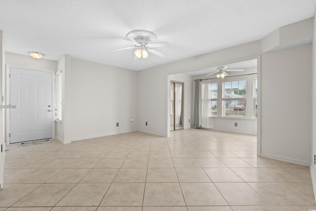 unfurnished room featuring ceiling fan, light tile patterned floors, and a textured ceiling