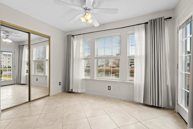 interior space featuring light tile patterned floors, a textured ceiling, and ceiling fan