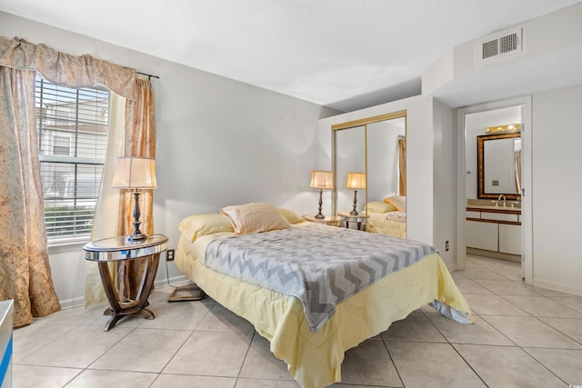 tiled bedroom featuring ensuite bathroom, sink, and a closet