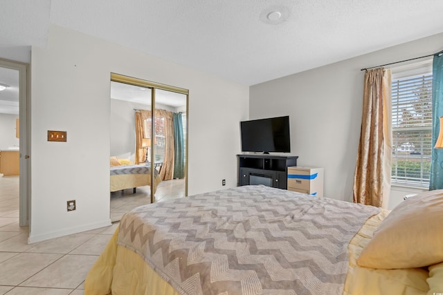 bedroom with light tile patterned floors, a textured ceiling, a closet, and multiple windows