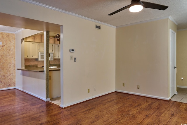 empty room with a textured ceiling, ceiling fan, light wood-type flooring, and ornamental molding