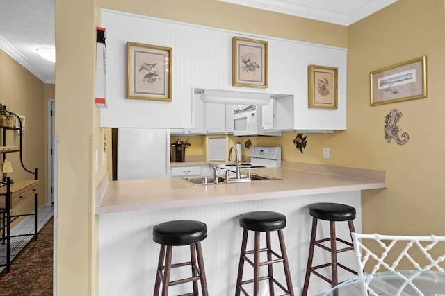 kitchen featuring white cabinets, a kitchen breakfast bar, ornamental molding, and sink