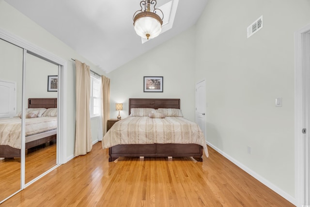 bedroom featuring high vaulted ceiling, light hardwood / wood-style flooring, and a closet