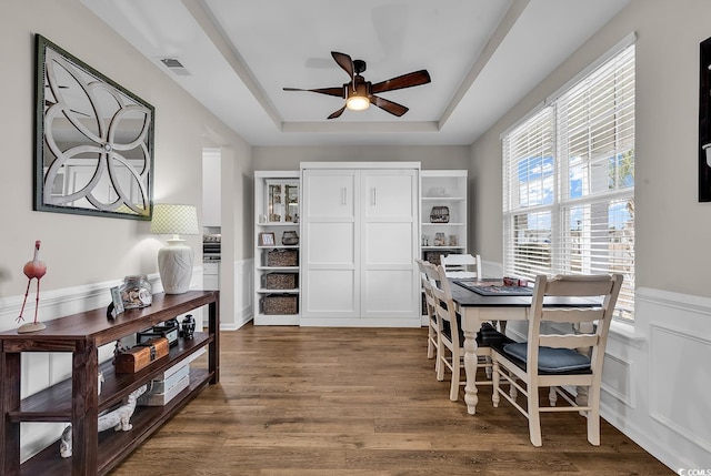 dining area featuring dark hardwood / wood-style flooring, a raised ceiling, and ceiling fan