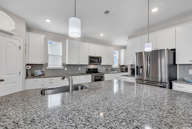 kitchen with stone counters, sink, decorative light fixtures, and appliances with stainless steel finishes