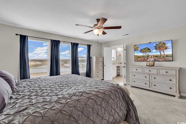 bedroom with ensuite bathroom, ceiling fan, and light colored carpet