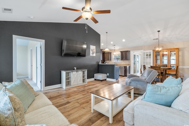 living room with a wealth of natural light, light hardwood / wood-style flooring, ceiling fan, and lofted ceiling