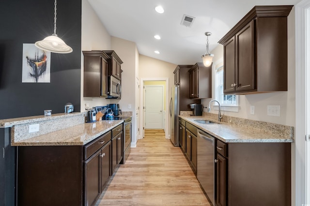 kitchen featuring decorative light fixtures, stainless steel appliances, lofted ceiling, and sink