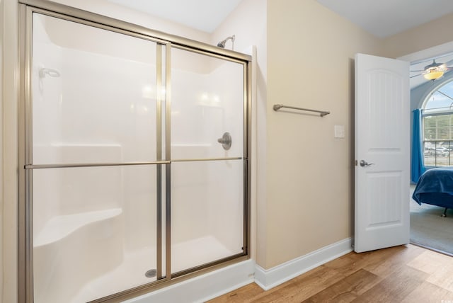 bathroom featuring hardwood / wood-style flooring, ceiling fan, and a shower with shower door