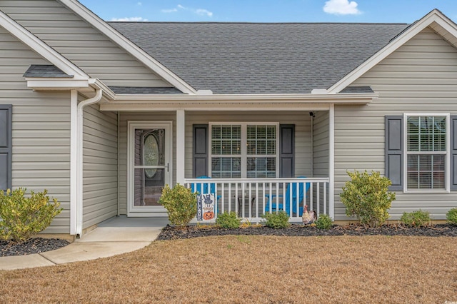 view of exterior entry featuring a porch and a lawn