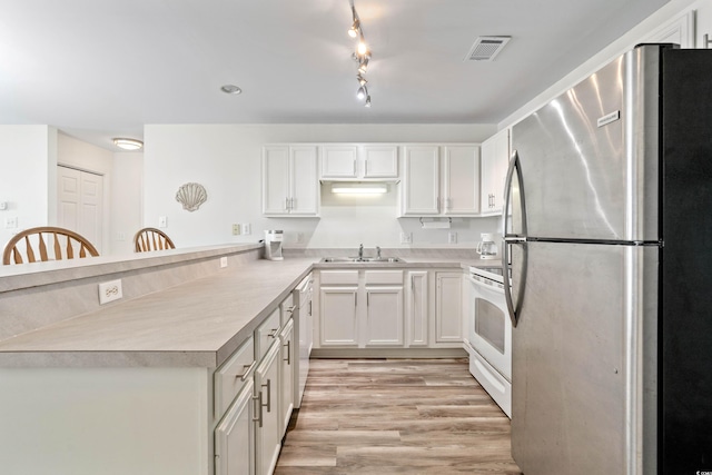 kitchen featuring white stove, white cabinets, sink, light hardwood / wood-style flooring, and stainless steel refrigerator