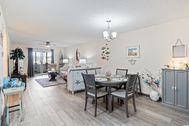 dining area with ceiling fan with notable chandelier, light hardwood / wood-style floors, and a textured ceiling