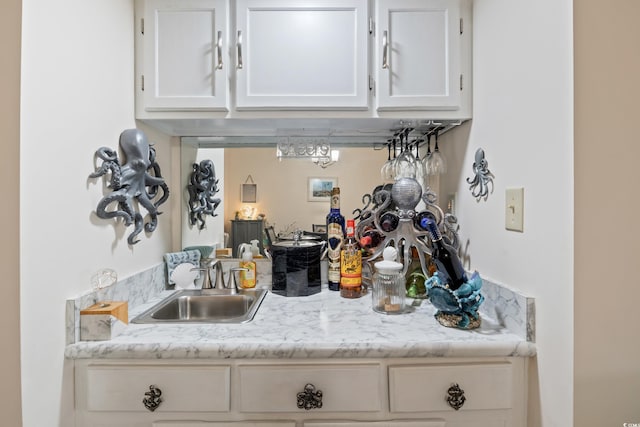 kitchen featuring white cabinets, light stone counters, and sink