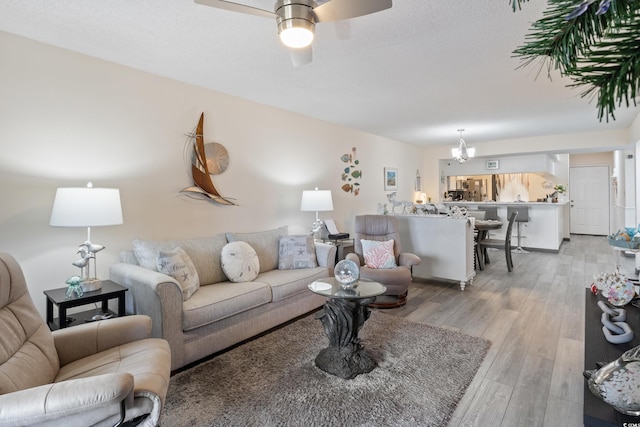 living room featuring ceiling fan with notable chandelier and light hardwood / wood-style floors