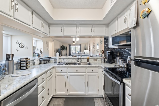 kitchen featuring sink, a textured ceiling, tasteful backsplash, white cabinetry, and stainless steel appliances