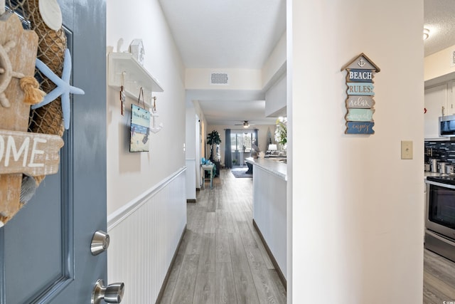 corridor featuring a textured ceiling and light wood-type flooring