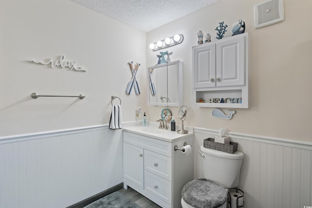 bathroom featuring vanity, a textured ceiling, and toilet