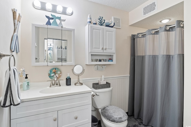 bathroom featuring vanity, a textured ceiling, toilet, and walk in shower